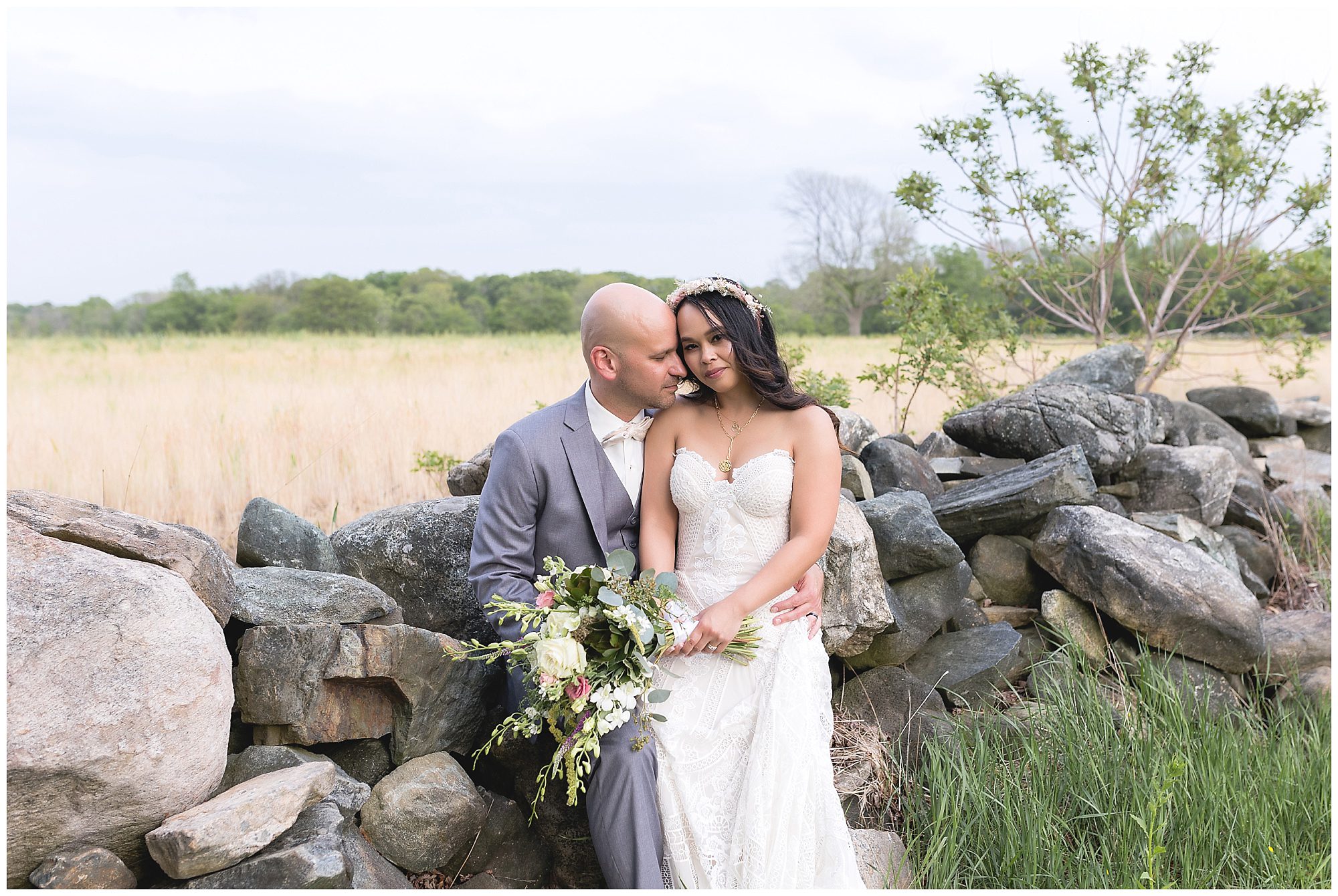 bride and groom sitting on a rock wall