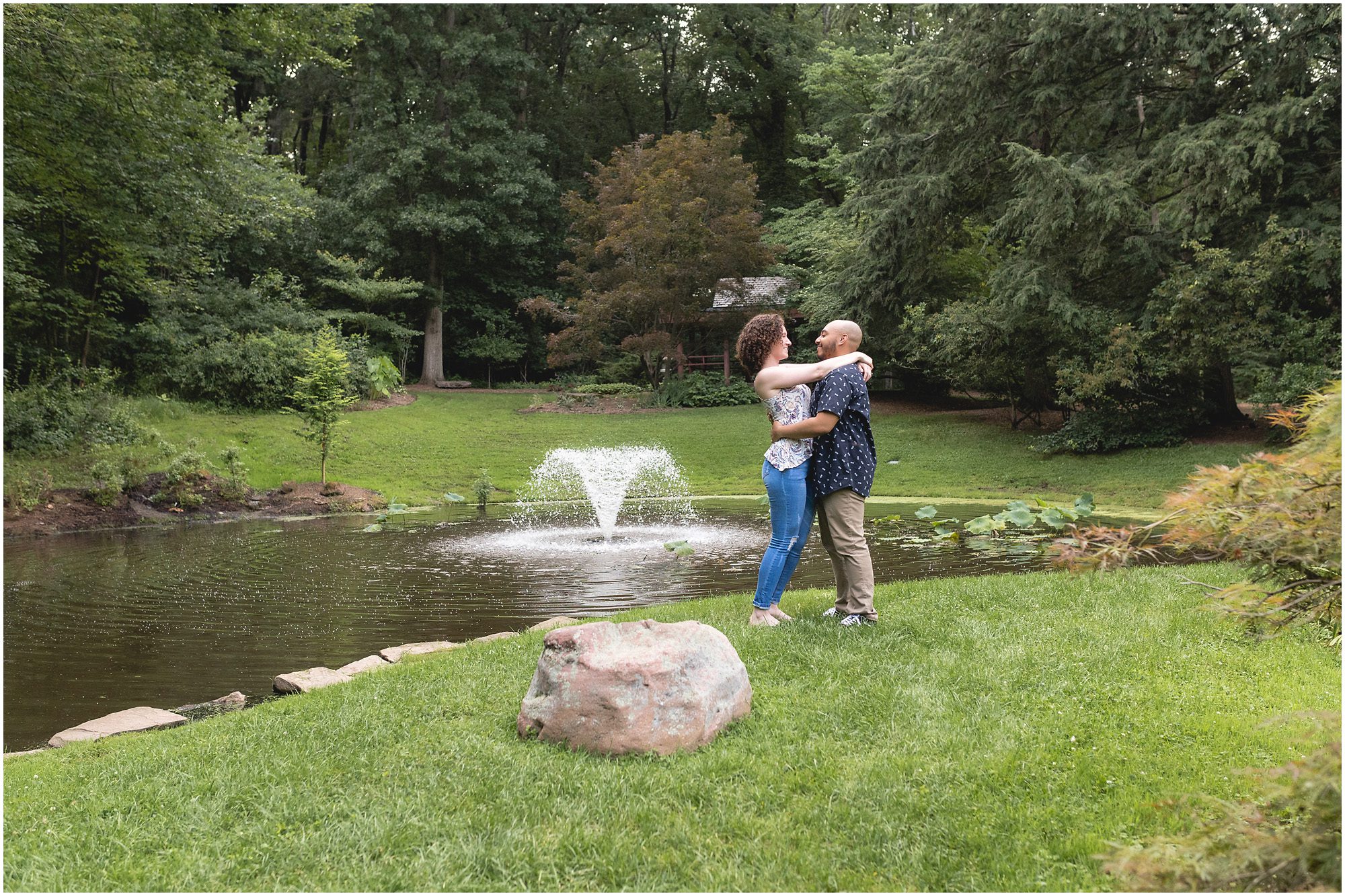 engaged couple by a pond with a fountain