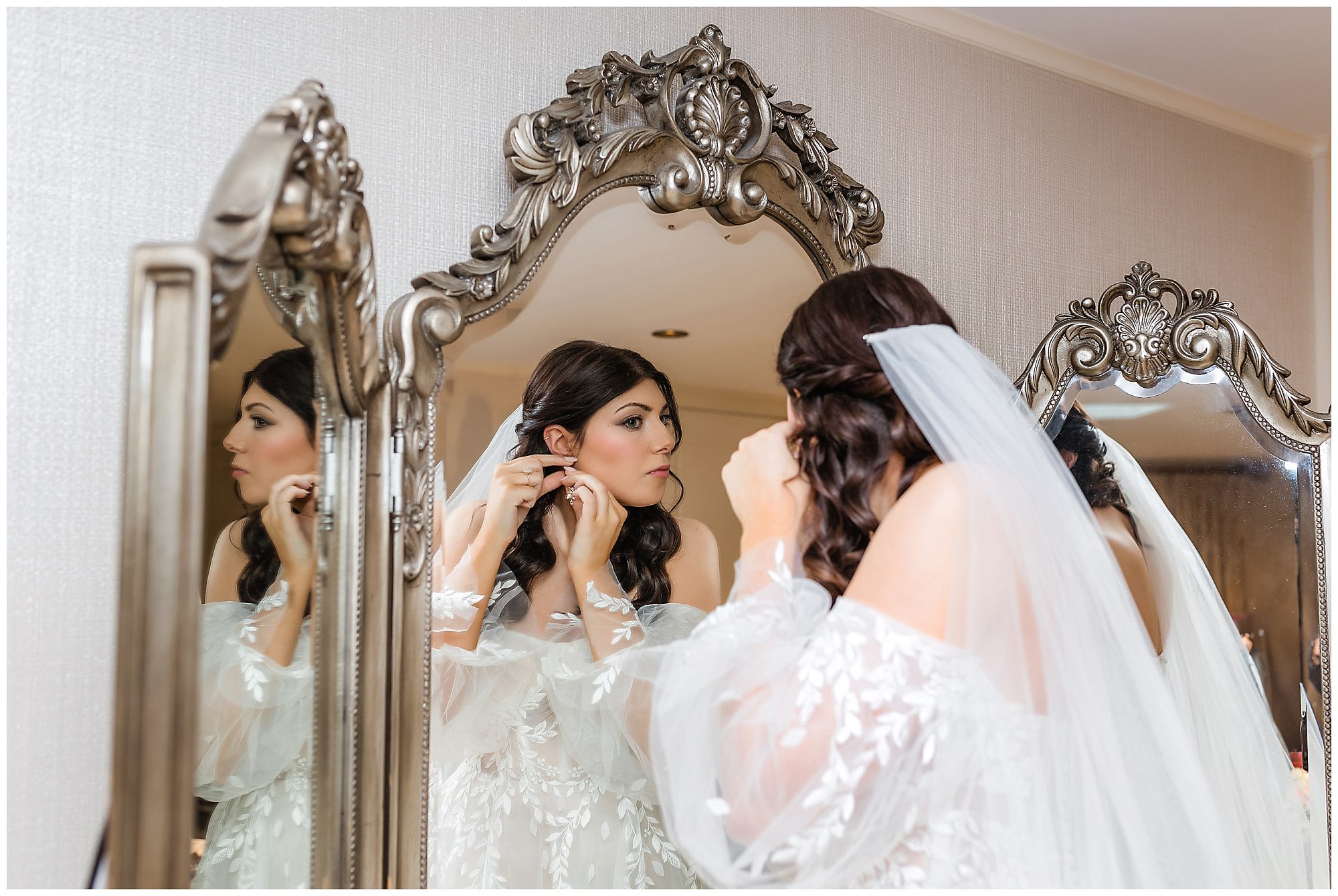 bride putting on jewelry in the mirror