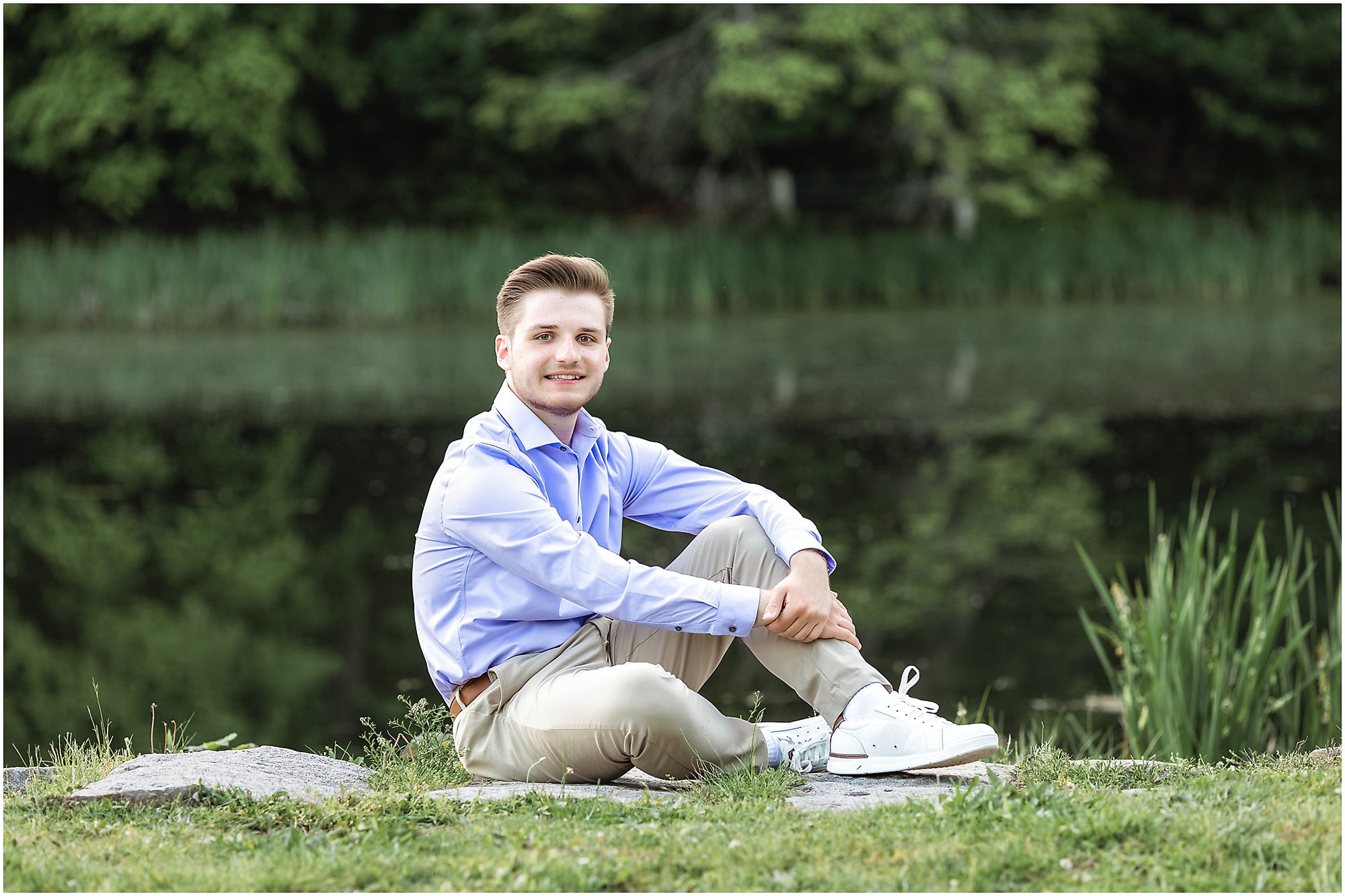 High school boy senior by the water rocks